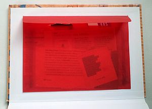 Une jolie enveloppe rouge transparente collée dans un cahier rigide